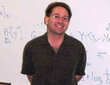 Scott Aaronson in front of a whiteboard of equations
