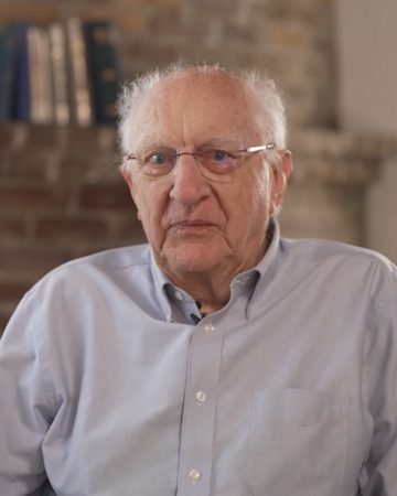 John Clarke in 2025, in a blue shirt