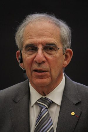 Michel Devoret in 2025, in a suit and red tie