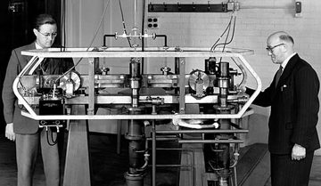 Louis Essen and Jack Parry standing beside the first caesium atomic clock at the National Physical Laboratory